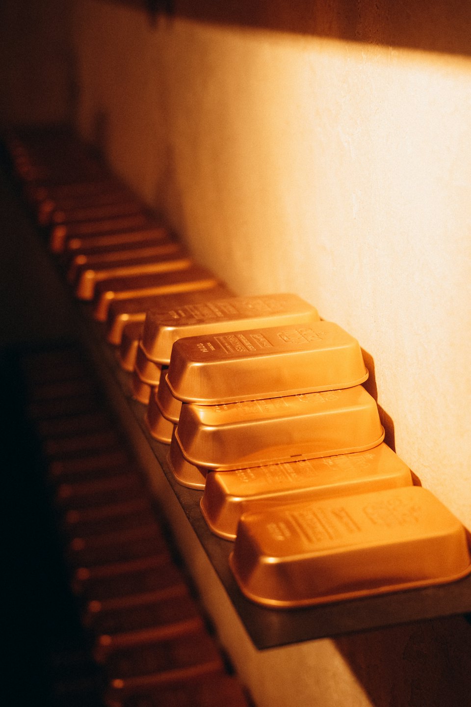 Rows of gold bars stacked neatly on a metal shelf.